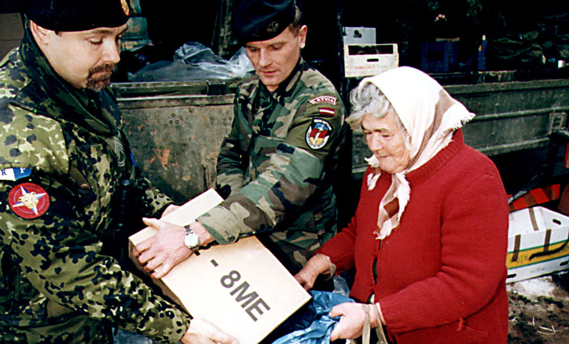 Danske soldater deler mad og tøj ud.