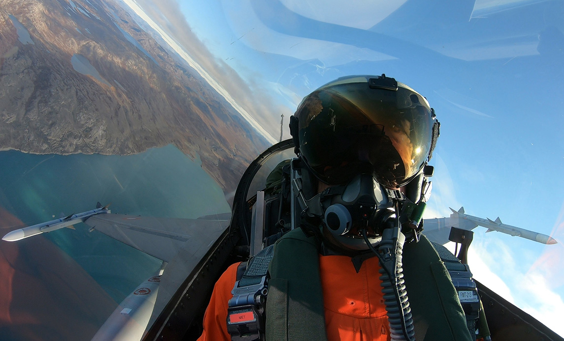 F16 kampfly over Grønland. Piloten kan ses i cockpit.