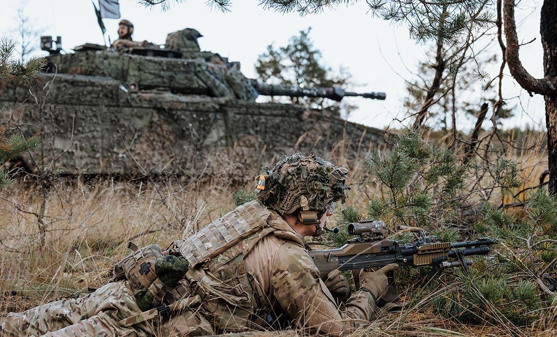 Skytte med let maskingevær bliver flankeret af et infanterikampkøretøj under indtagelse af et mål.
