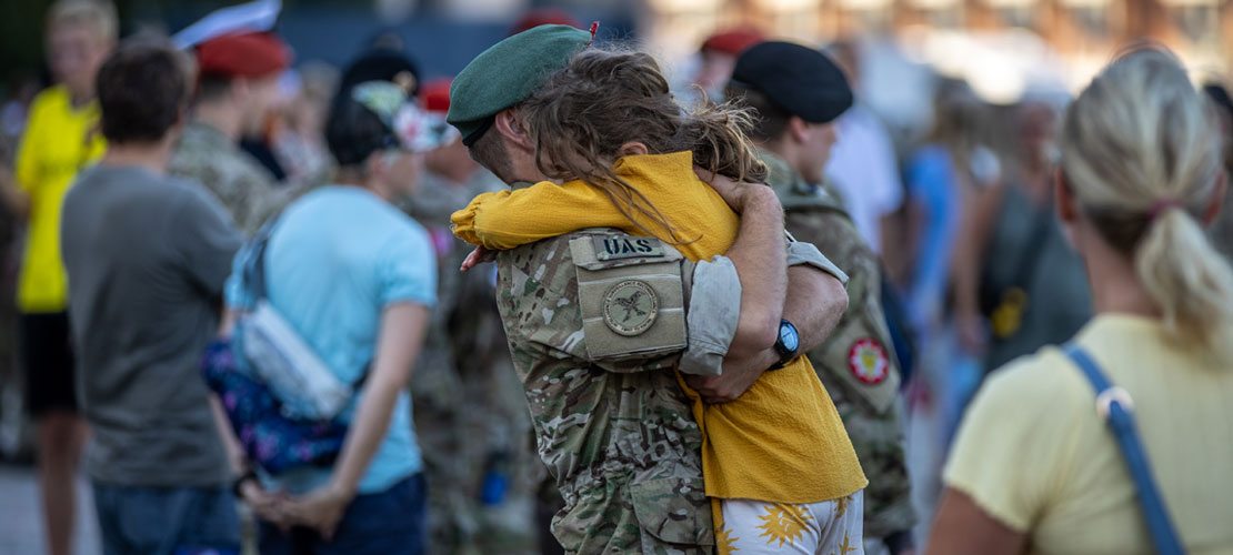 En mand i uniform løfter sin datter til et kram
